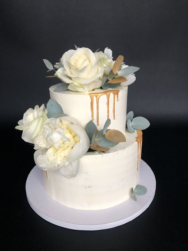 White and gold wedding cake with fresh flowers